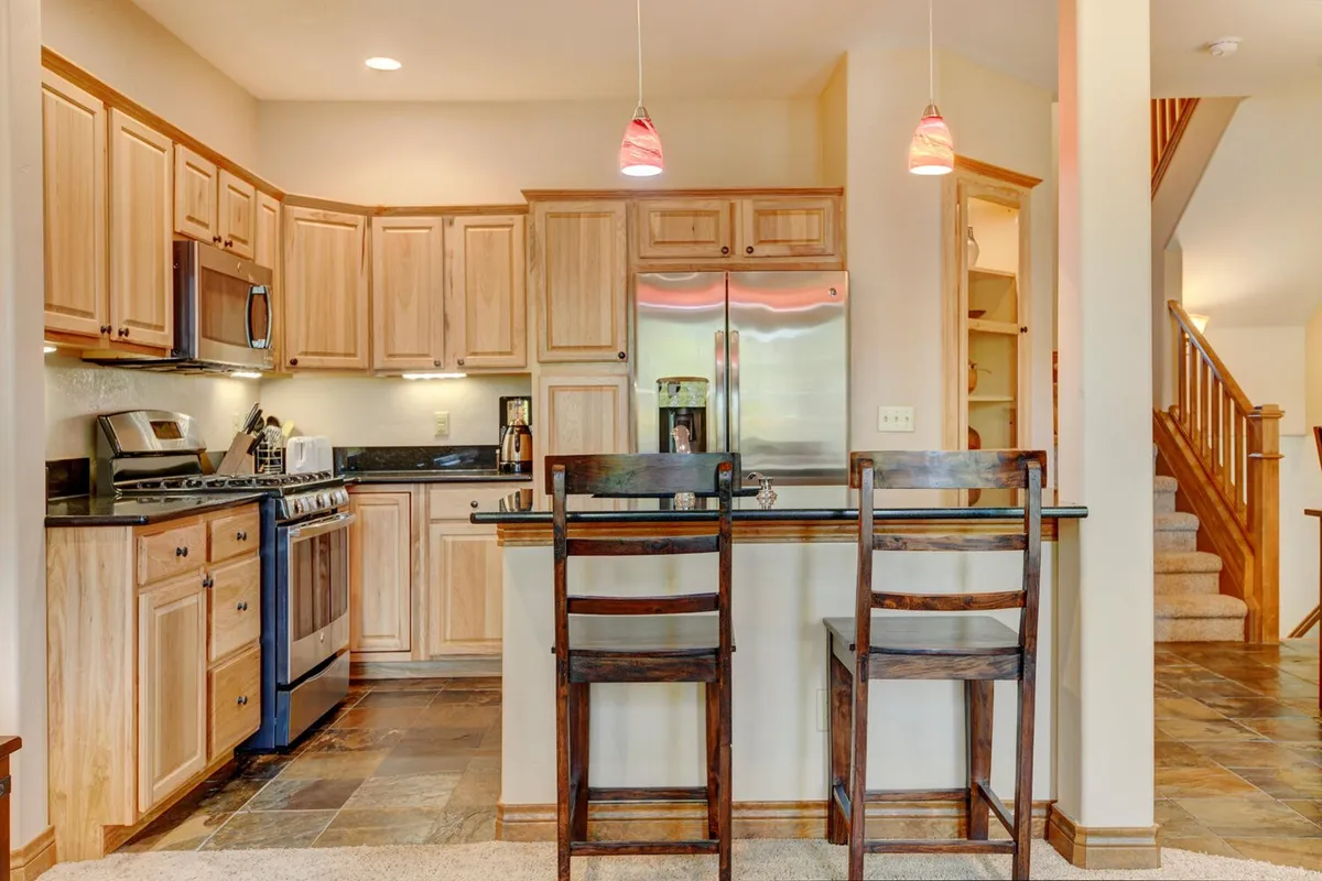 A warm, inviting kitchen featuring a large kitchen island, stainless steel appliances, and rich wood cabinets. The space is bustling with activity, perfect for cooking, entertaining, and sharing family meals. Subtle holiday touches hint at festive gatherings, while the open layout encourages conversation between chefs and guests.