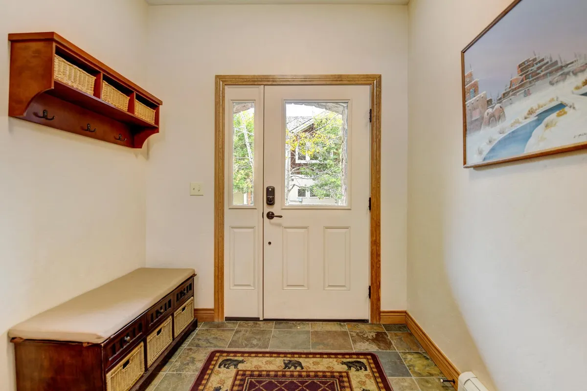 A welcoming entryway with a front door, bench seating, and tasteful wall art. The space is designed for greeting guests, storing outdoor gear, and creating a positive first impression as you step inside.