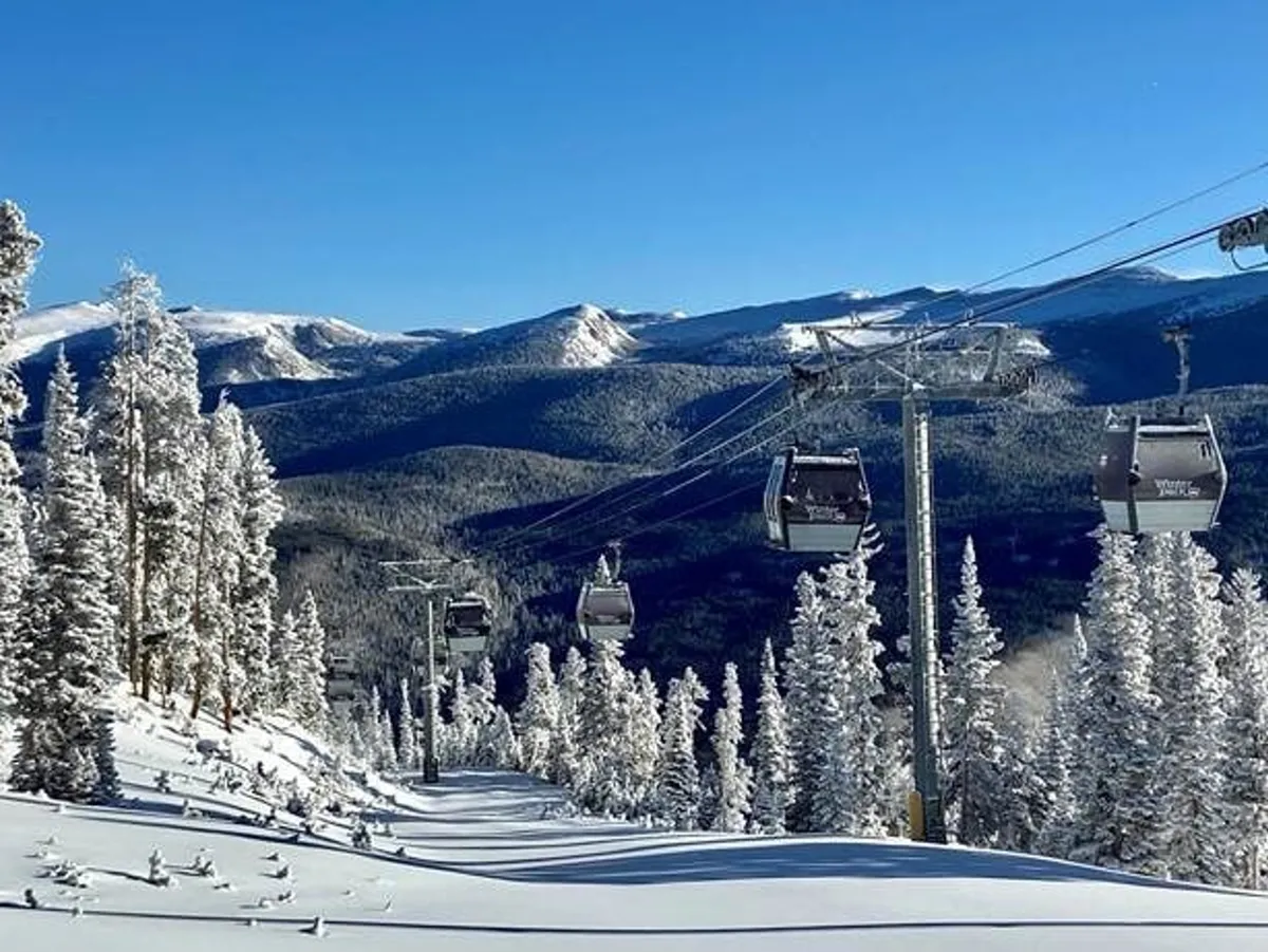 A stunning exterior shot of ski lifts gliding over snow-covered slopes framed by pine trees and a majestic mountain range. The tranquil, scenic setting is alive with skiing, snowboarding, and snowshoeing possibilities.