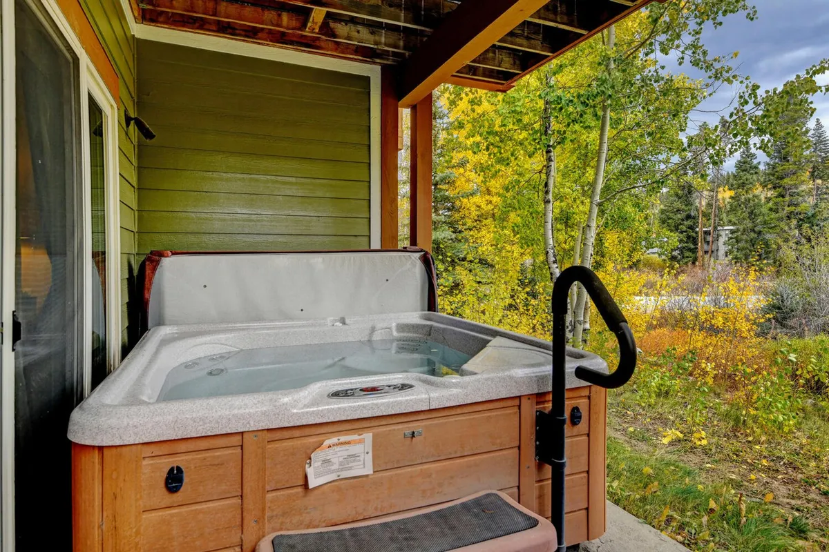 A tranquil outdoor deck featuring a private hot tub overlooking the surrounding natural beauty. The setting is serene and inviting, ideal for soaking after a day on the slopes or stargazing in the fresh mountain air.