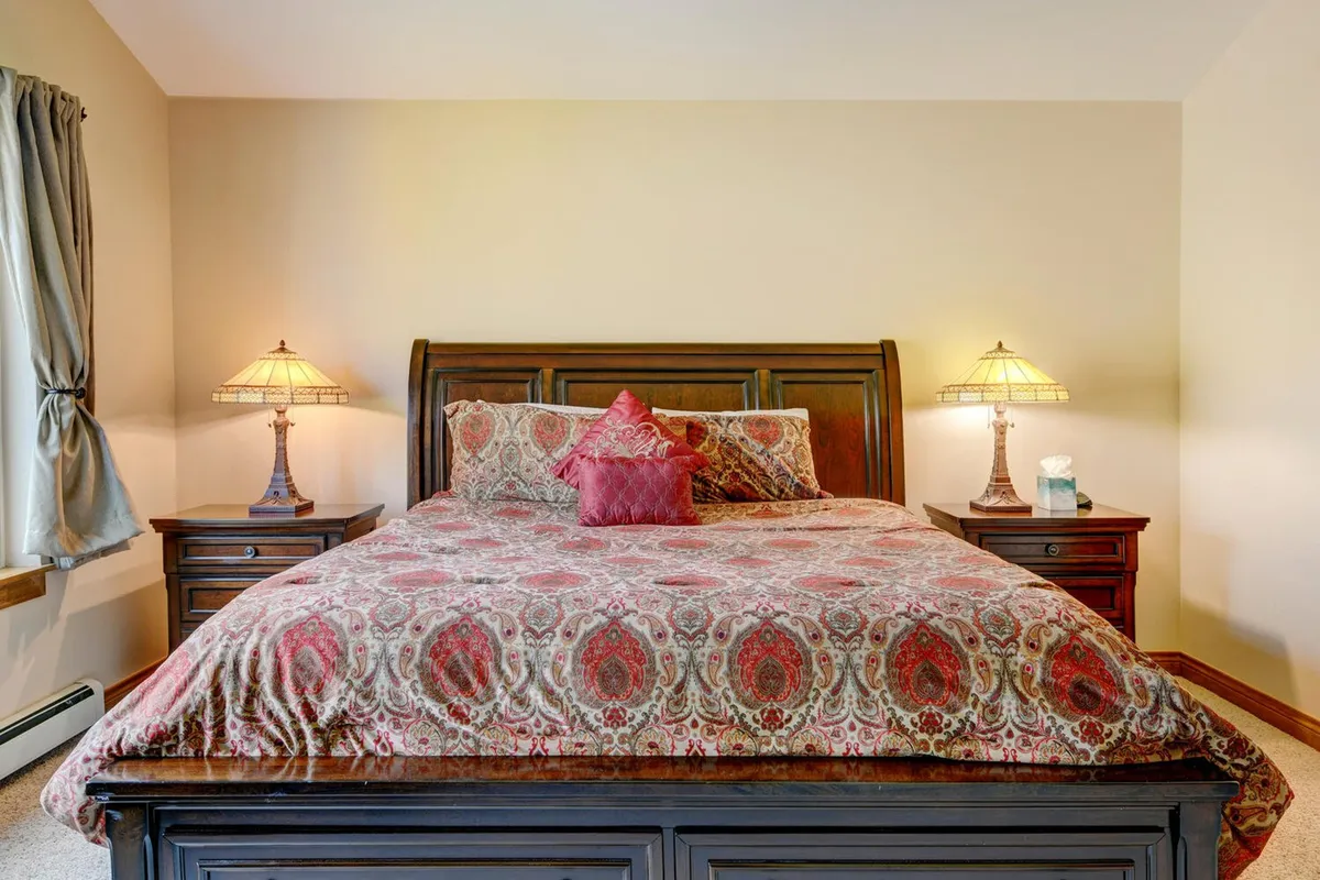 A cozy bedroom featuring a bed with ornate bedding and soft pillows, flanked by elegant nightstands with warm-glowing lamps. The inviting decor and soft lighting create a restful ambiance, ideal for unwinding after a day of adventure.